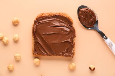 Tasty toast with hazelnut butter and nuts on color background