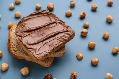 Tasty toasts with hazelnut butter and nuts on color background
