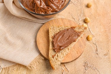 Delicious toast with hazelnut butter on color background