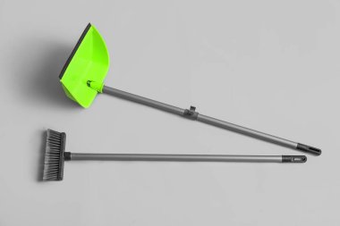 Cleaning broom with green dustpan on white background
