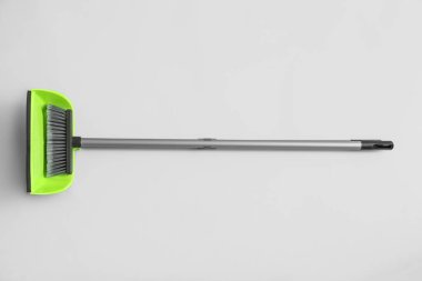 Cleaning broom with green dustpan on white background