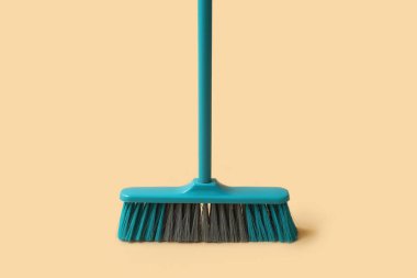 Blue cleaning broom on orange background