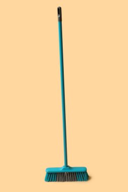 Blue cleaning broom on orange background