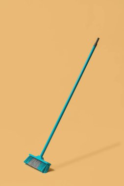 Blue cleaning broom on orange background