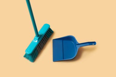 Cleaning broom and dustpan on orange background