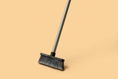 Broom for cleaning on orange background