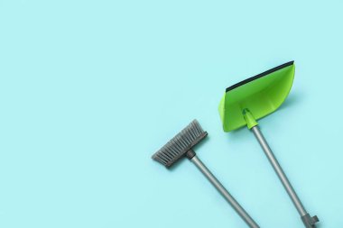 Broom with plastic dustpan on color background