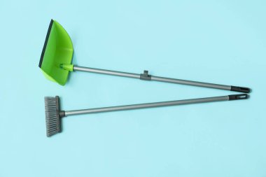 Broom with plastic dustpan on color background