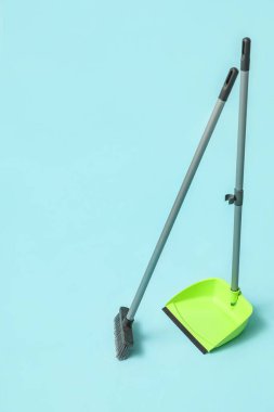 Broom with plastic dustpan on color background