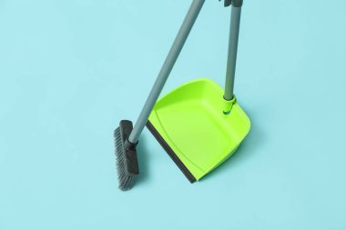 Broom with plastic dustpan on color background