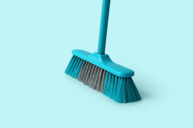 Blue plastic broom on color background
