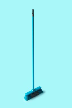 Blue plastic broom on color background
