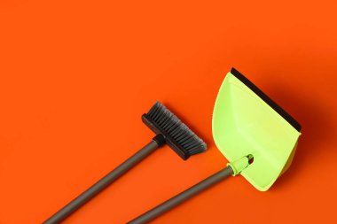 Cleaning broom with green dustpan on color background