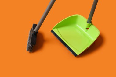 Plastic dustpan with cleaning broom on color background