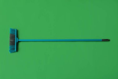 Blue cleaning broom on green background