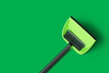 Dustpan with cleaning broom on green background