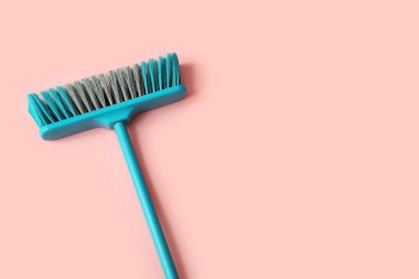 Blue cleaning broom on pink background
