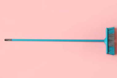 Blue cleaning broom on pink background