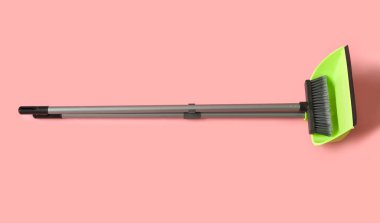 Dustpan with cleaning broom on pink background