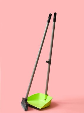Dustpan with cleaning broom on pink background
