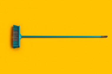 Blue cleaning broom on yellow background