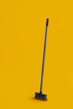Plastic cleaning broom on yellow background