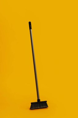 Plastic cleaning broom on yellow background