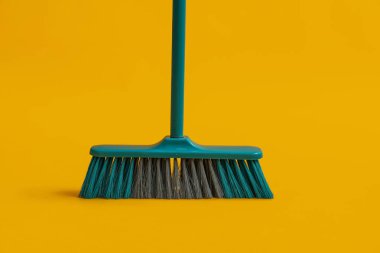 Plastic broom for cleaning on yellow background