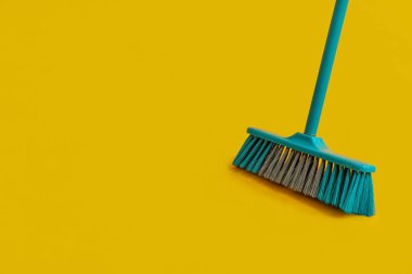 Plastic broom for cleaning on yellow background