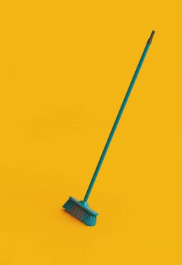 Plastic broom for cleaning on yellow background