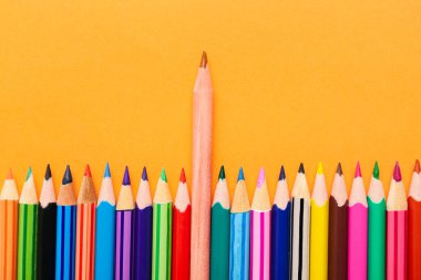 Set of colorful pencils on orange background, closeup