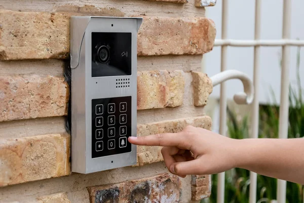Child using modern intercom on brick wall, closeup