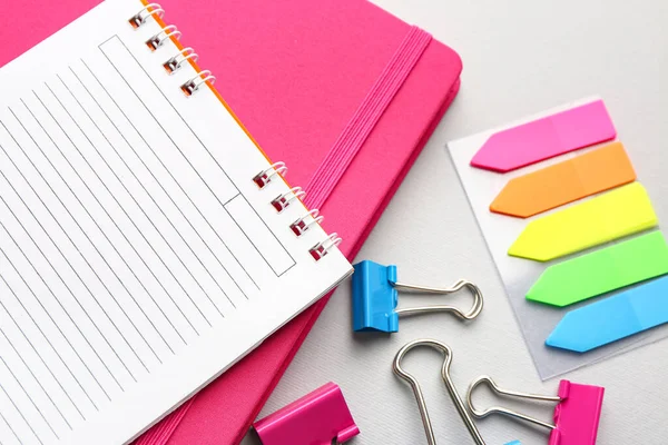 Notebooks, sticky notes and paper clips on light background, closeup