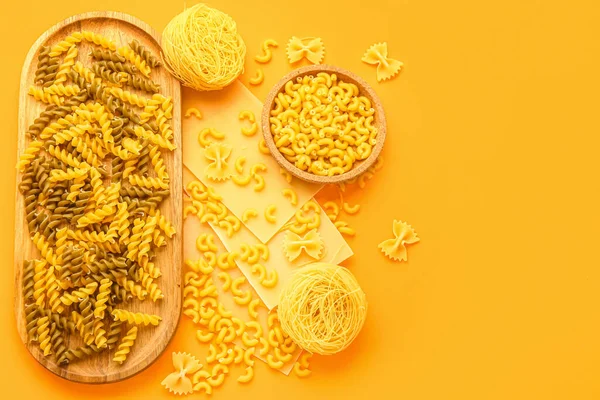 Composition with different types of uncooked pasta on color background