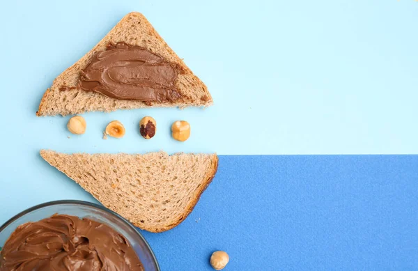 Toasts with hazelnut butter and nuts on color background