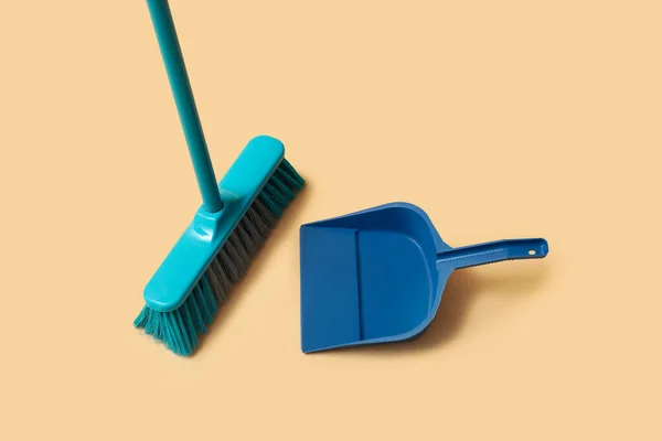 Cleaning broom and dustpan on orange background