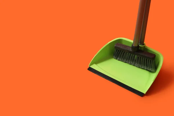 Plastic dustpan with cleaning broom on color background