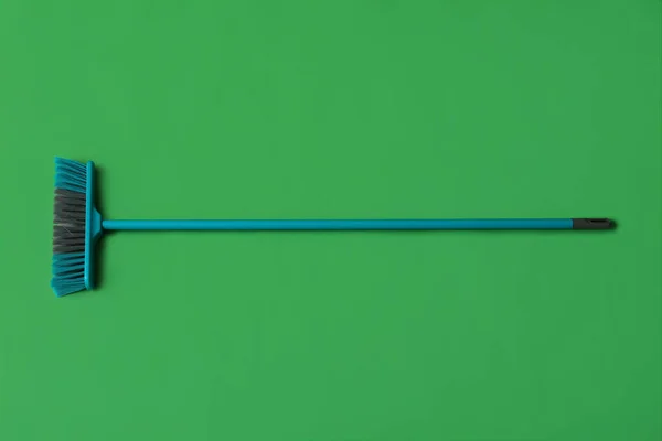 Blue cleaning broom on green background