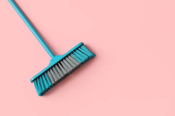 Blue cleaning broom on pink background