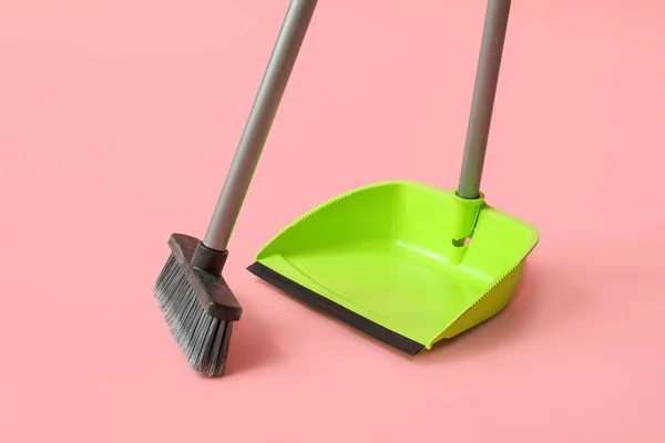 Dustpan with cleaning broom on pink background