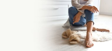 Barefoot woman with slippers sitting on floor at home. Banner for design