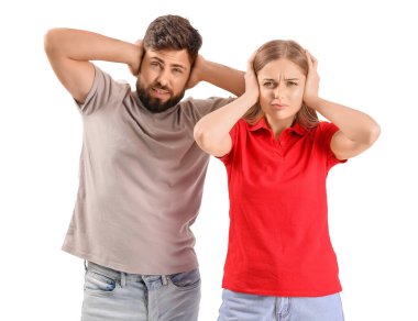 Young couple suffering from loud noise on white background