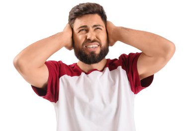 Irritated young man suffering from loud noise on white background