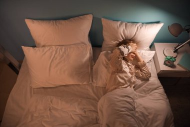 Young woman lying in bed at night