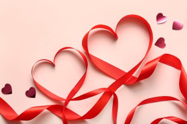 Red ribbon with hearts on beige background. Valentine's Day celebration