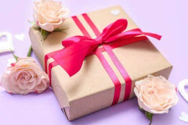 Beautiful gift box and rose flowers on color background, closeup. Valentine's Day celebration