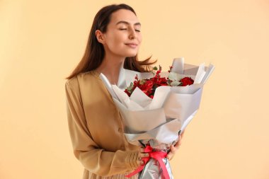 Young woman with bouquet of flowers on beige background. Valentine's Day celebration
