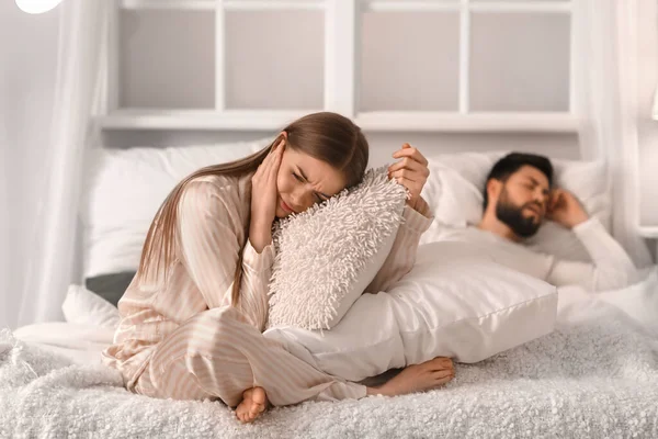 Young woman cannot sleep because of snoring her husband in bedroom at night