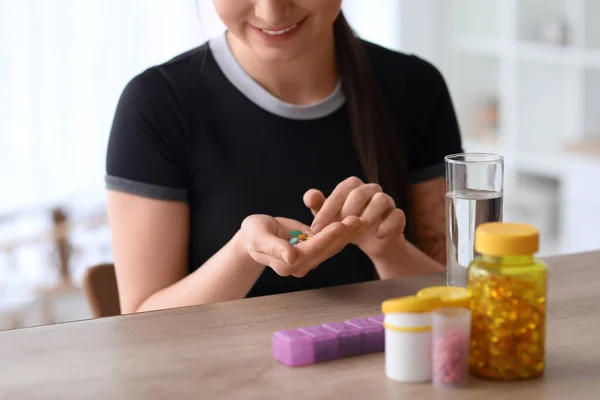 Sporty young woman with vitamin supplements at home, closeup