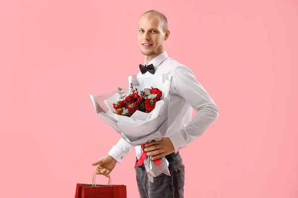 Young man with bouquet of flowers and bag on pink background. Valentine\'s Day celebration